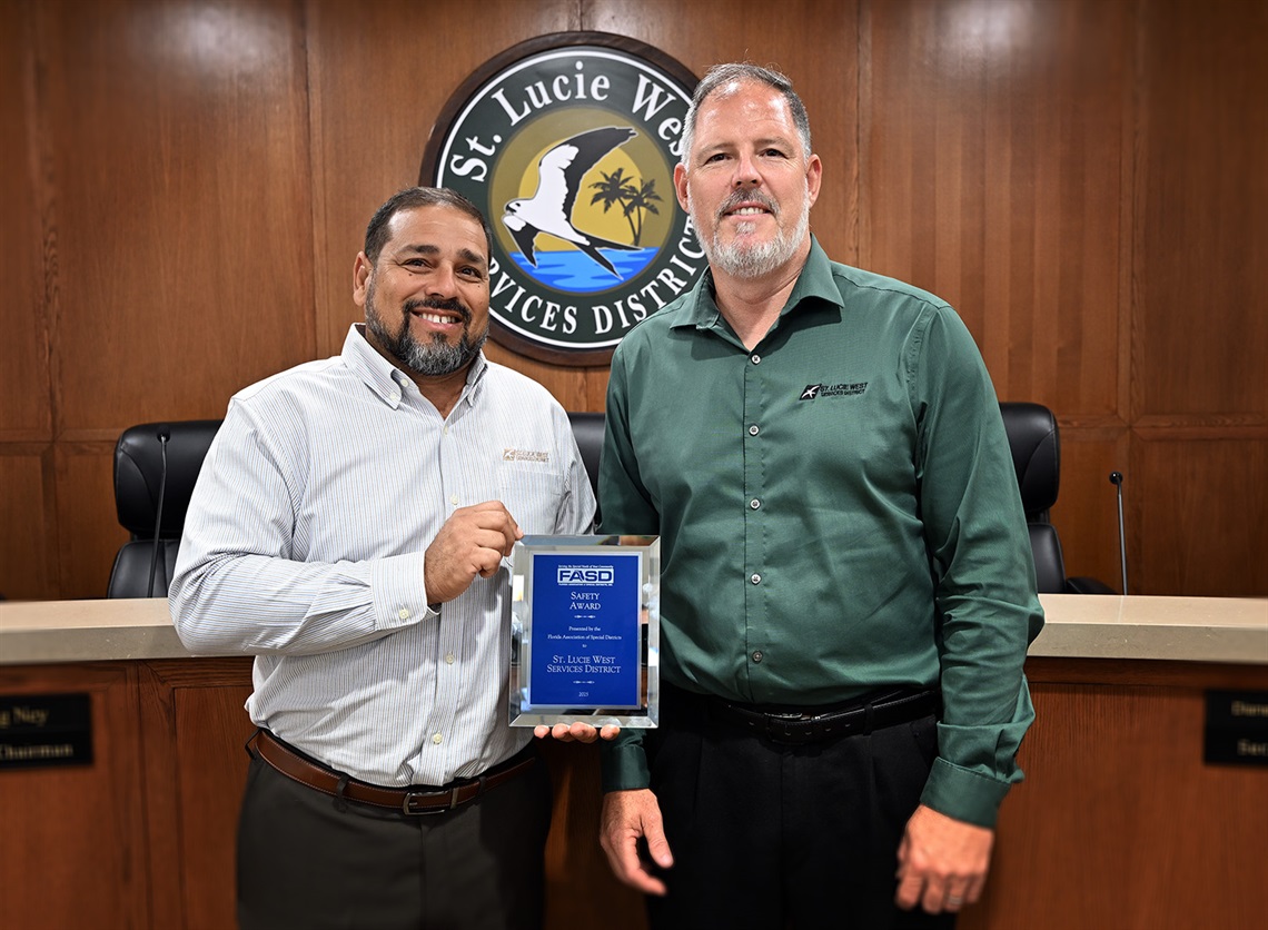 District Manager and Assiatnt District Manager holding safety award plaque.